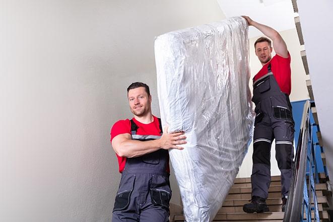 man carrying a heavy box spring out of a room in Hanover